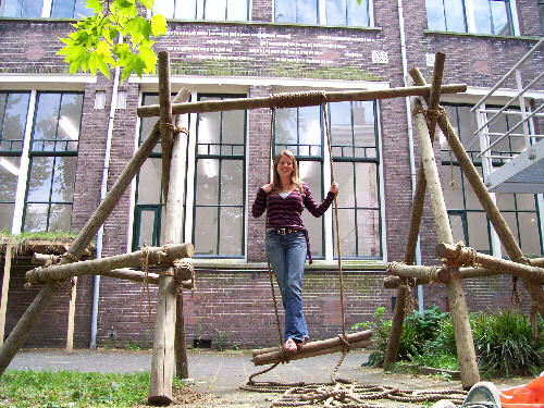Kunstenares Marjolein Nolet, staand op haar kunstwerk 'Schommelend', met op de achtergrond de tekst in Morse-code